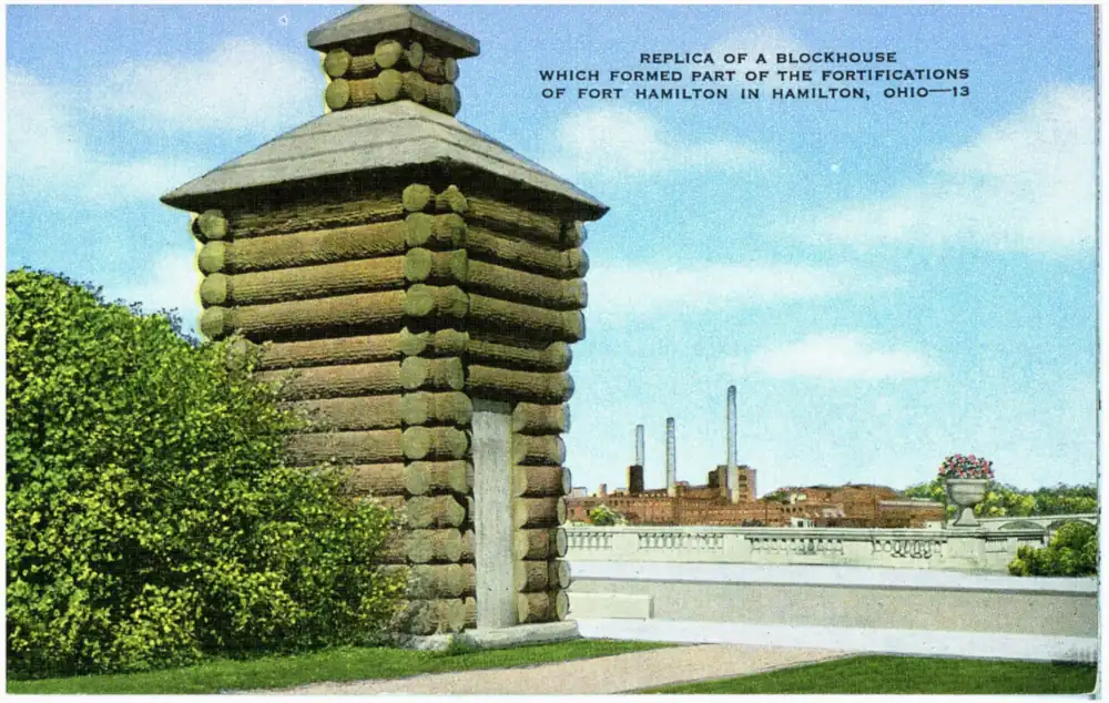 Postcard of a reconstructed log blockhouse with pointed stockade posts